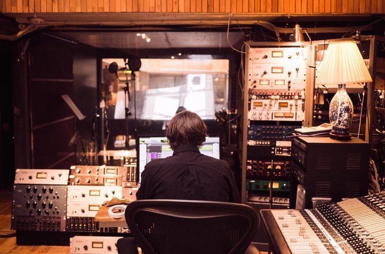 man in front of studio mixer and receiver