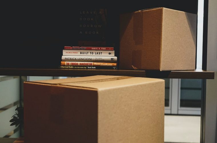 two brown boxes and DVD cases on rack