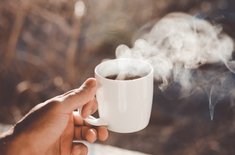 person holding white ceramic cup with hot coffee