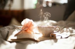 teacup on book beside pink flower decor