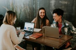 three people sitting in front of table laughing together